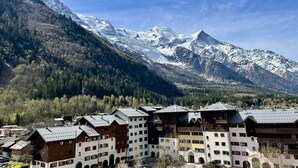 A mountain resort with chalet-style buildings, a ski slope, and snow-capped peaks in the background. - Nice flat with balcony view Mont Blanc | Parking (Chamonix-Mont-Blanc)