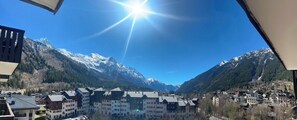 A mountain town with buildings, a clear sky, and snow-capped mountains in the background. - Nice flat with balcony view Mont Blanc | Parking (Chamonix-Mont-Blanc)