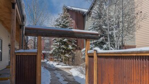 A snow-covered pathway leading to a wooden gate, with a building and a snow-laden tree in the background. - Lulu 6J Walk to Lift 7 + Pool & HotTub - 2 Bedroom+Loft, 3 Bathroom, Sleeps 6 (Telluride)