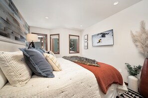 Relax in a serene retreat with a large bed, wooden headboard, and a view of the surrounding trees.