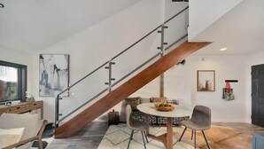 A modern living room with a wooden staircase, a round dining table with chairs, and a sofa. - Lulu 6J Walk to Lift 7 + Pool & HotTub - 2 Bedroom+Loft, 3 Bathroom, Sleeps 6 (Telluride)