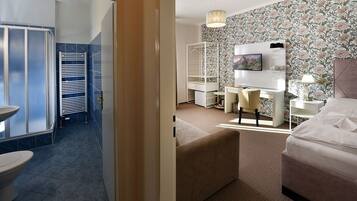 Une chambre d’hôtel moderne équipée d’une salle de bain, d’un lit, d’un bureau et d’une télévision.