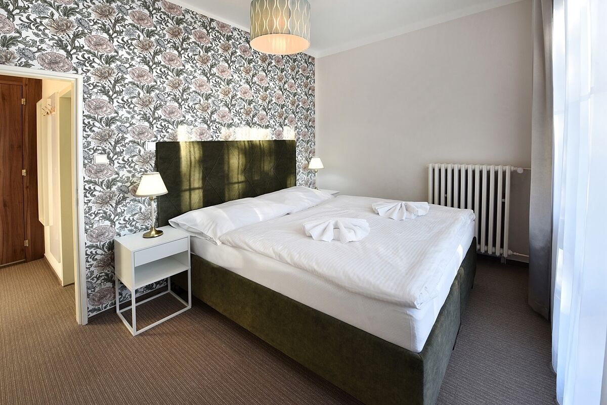 A hotel room with a bed, a nightstand, a lamp, and a radiator.