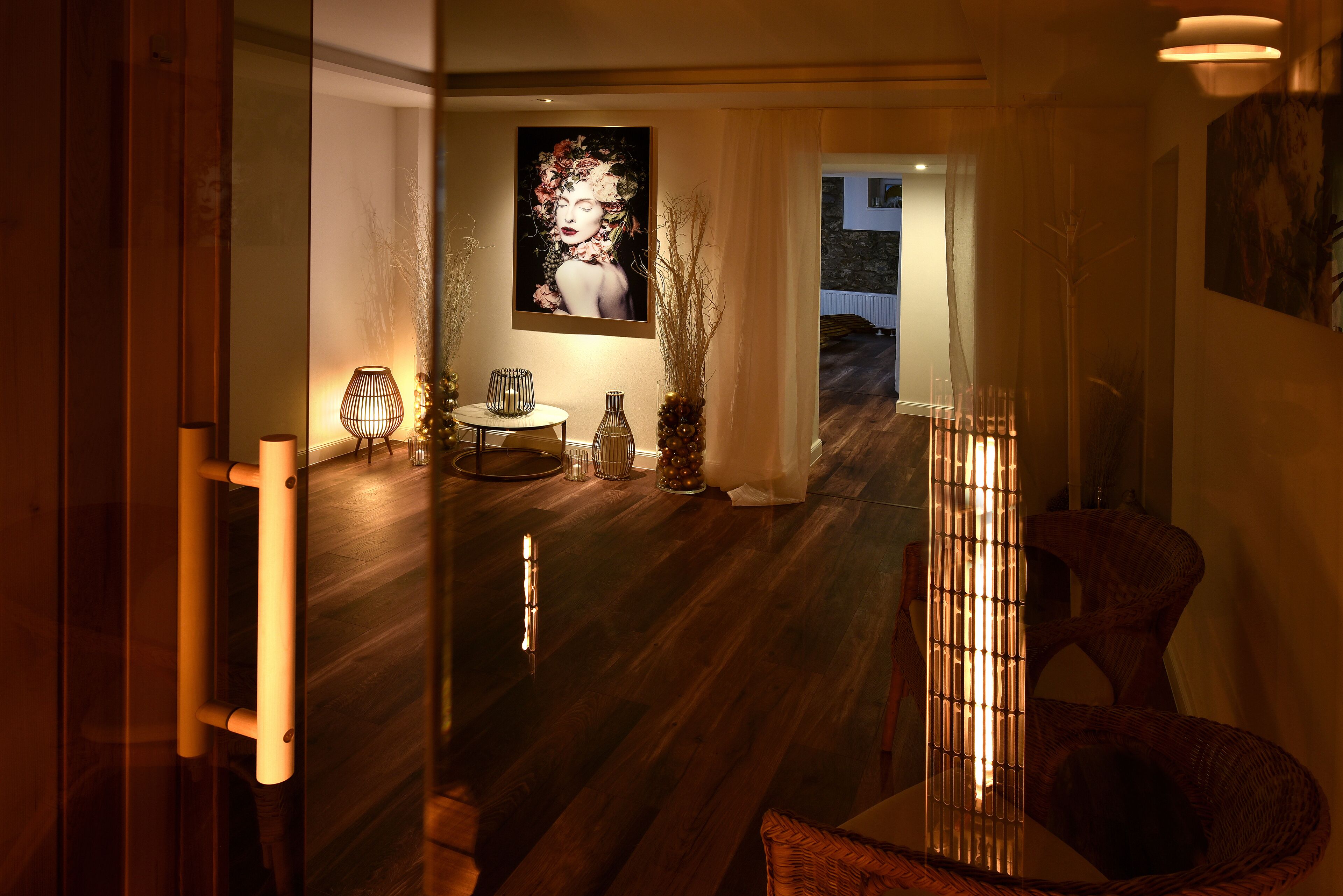 A modern interior with a wooden floor, a glass partition, and a dining area with a table and chairs.
