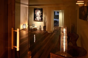 Un interior moderno con piso de madera, un separador de vidrio y un área de comedor con mesa y sillas.