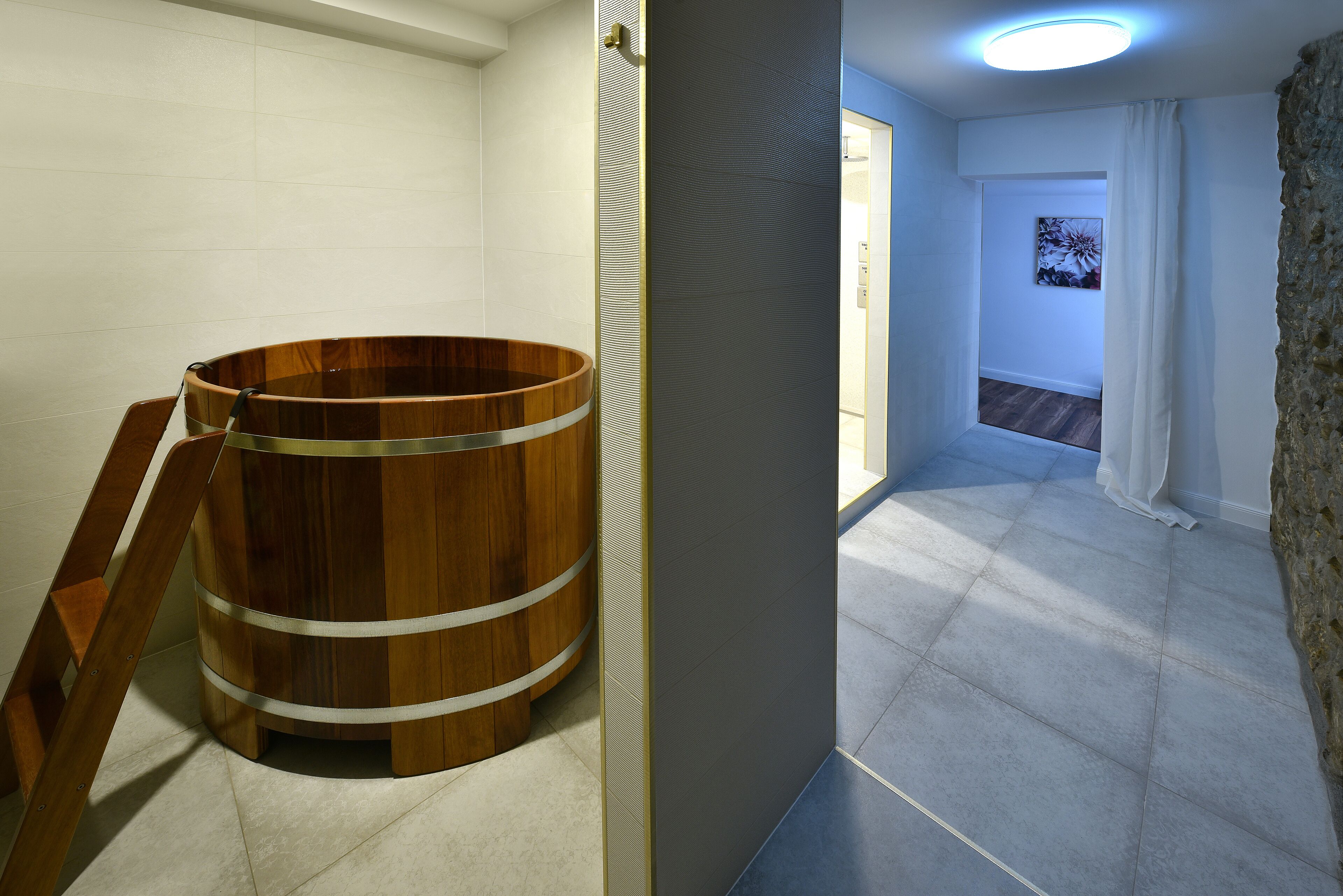 A wooden bathtub in a bathroom with white walls and a tiled floor.