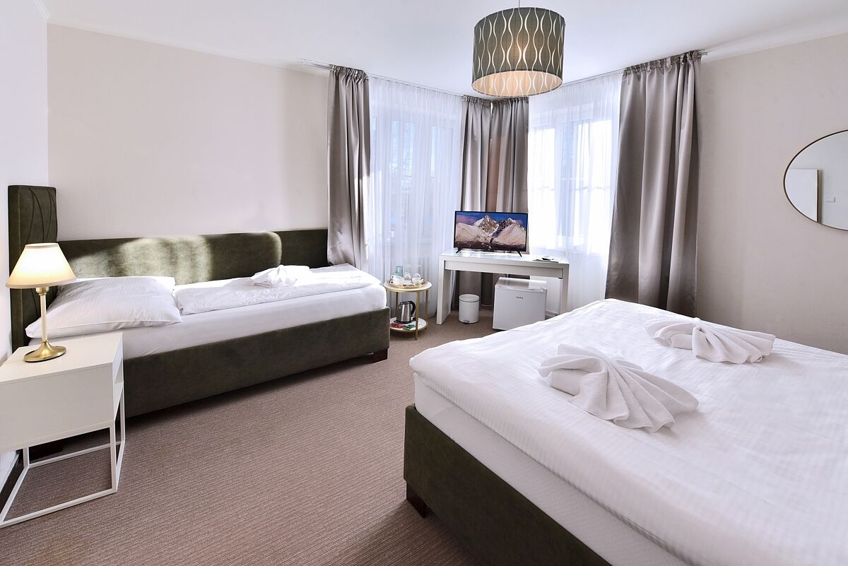 A hotel room with two beds, a desk, a TV, and a lamp.