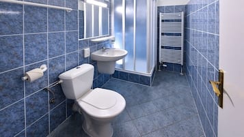 Ein Badezimmer mit blauen Fliesen, einer Toilette, einem Waschbecken, einer Dusche und einem Handtuchhalter.