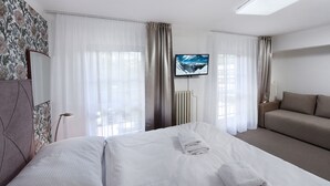 Een hotelkamer met een bed, een slaapbank, een televisie en een radiator.
