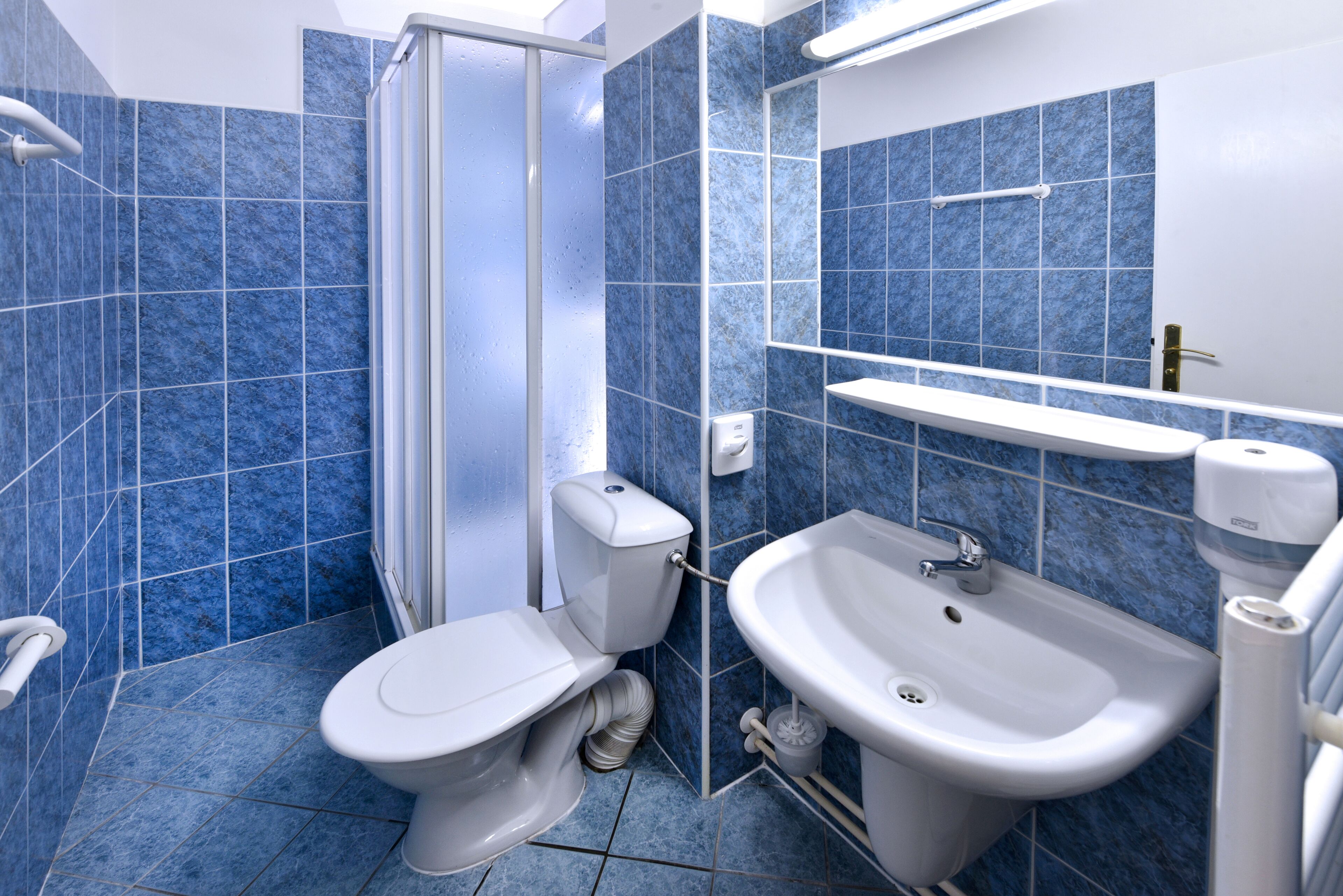 A bathroom with a toilet, sink, and shower.