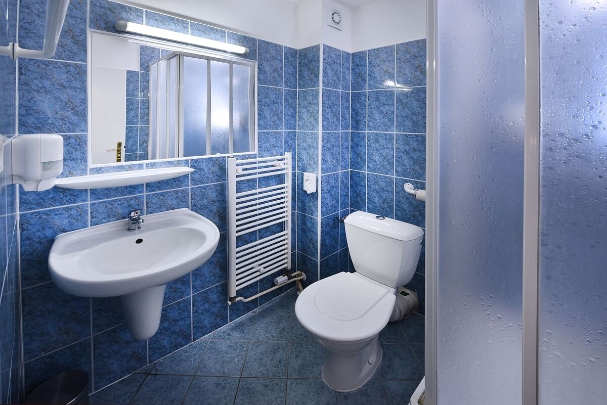 A bathroom with blue tiles, a white sink, a toilet, and a mirror.