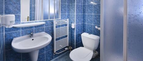 A bathroom with blue tiles, a white sink, a toilet, and a mirror.