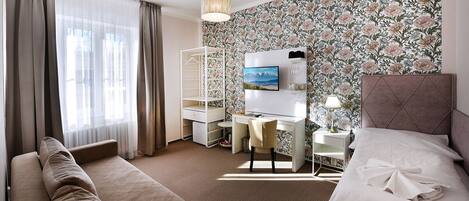 A hotel room with a bed, a desk, a chair, a wardrobe, and a large window with curtains.