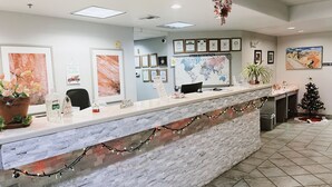 A reception area with a marble counter, framed certificates, a world map, and a small decorated Christmas tree. - North Shore Inn (Overton)