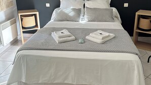 A neatly made bed with white linens, two bedside tables with baskets, and a dark wall with two wall-mounted lights. - Villa in a green setting, not overlooked, facing the village of Bargemon (bargemon)