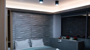 A modern bedroom with a bed, bedside tables, a built-in bench, and a window with a view. - Kastren Rooms (Chania)