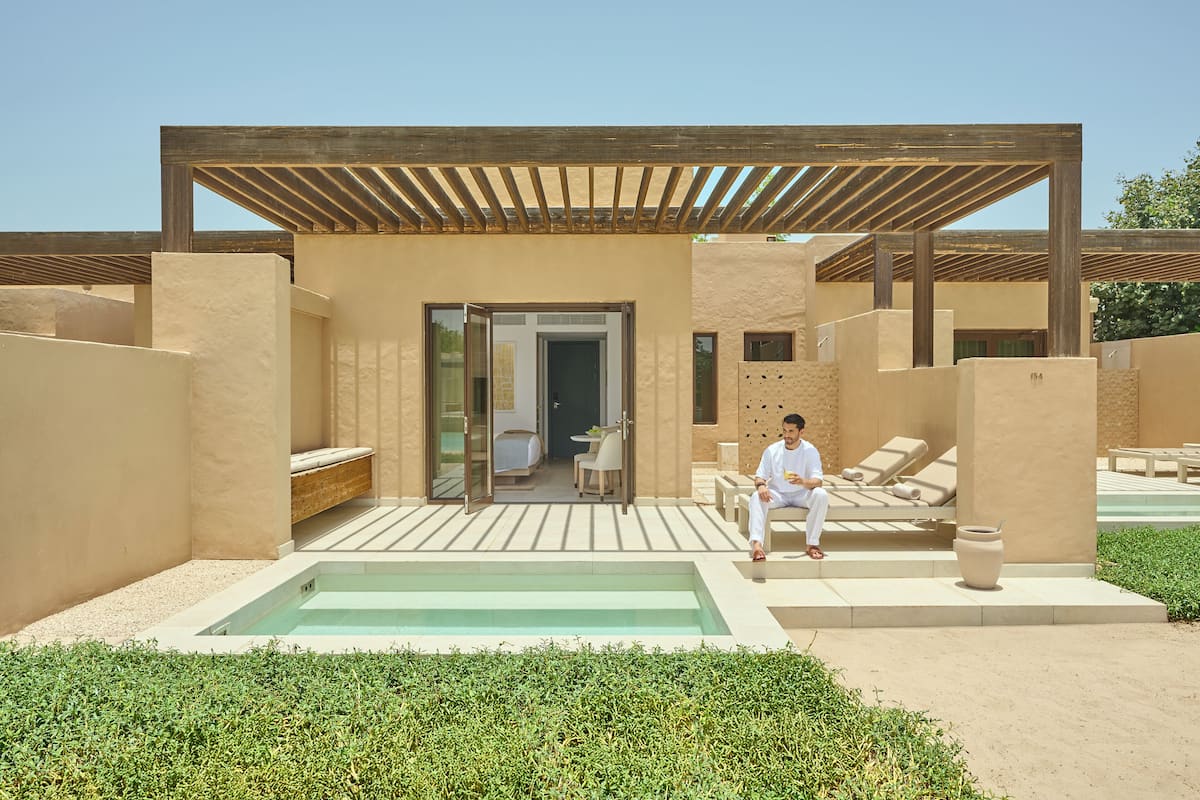 Un espace de détente extérieur moderne, doté d’une piscine, d’une pergola en bois et de coins salon.