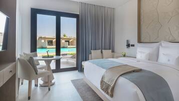 A modern hotel room with a large bed, a desk, and a view of a swimming pool.