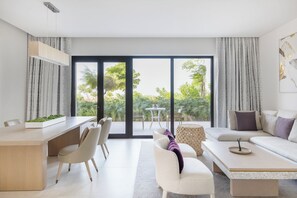 Een moderne woonkamer met een bank, een eettafel met stoelen, een keuken met aanrecht en kastjes, en grote schuifdeuren die uitkomen op een balkon met beplanting.