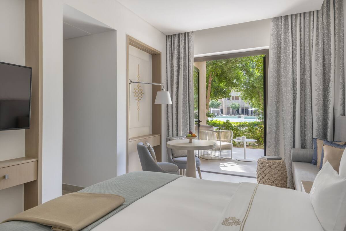 Une chambre d’hôtel équipée d’un lit, d’une télévision, d’un bureau et d’un balcon avec une table et des chaises.