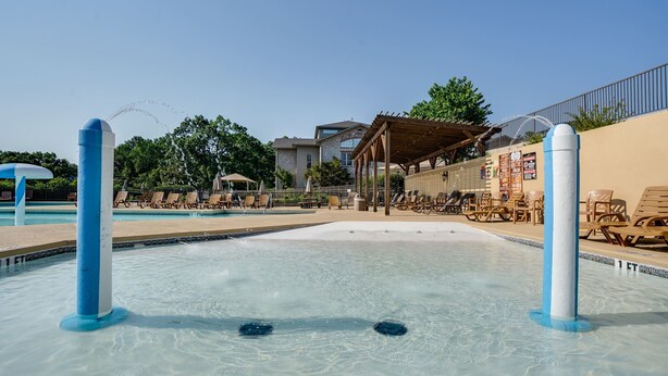 Un área de piscina con agua cristalina, sillas de descanso y una zona de estar techada.