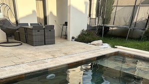A swimming pool with a stone tile design, surrounded by a patio area with outdoor furniture and a covered seating area. - Villa design swimming pool Avignon festival (Avignon)