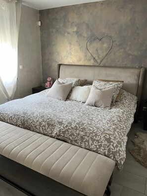 A bedroom with a large bed, a headboard, and a heart-shaped decoration on the wall.