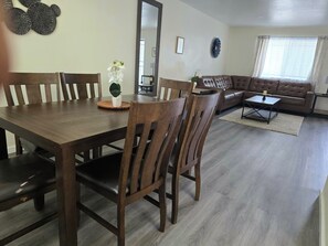 Zona pranzo con tavolo e sedie in legno, un divano e un tavolino.