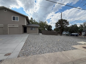 A residential property with a garage, a covered driveway, and a gravel area.