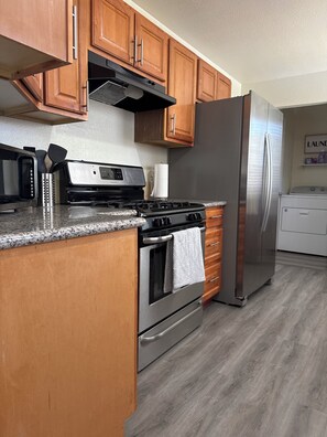 A kitchen with wooden cabinets, a stainless steel refrigerator, a gas stove, and a microwave.
