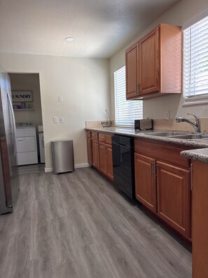 A kitchen with wooden cabinets, a stainless steel sink, and a dishwasher.