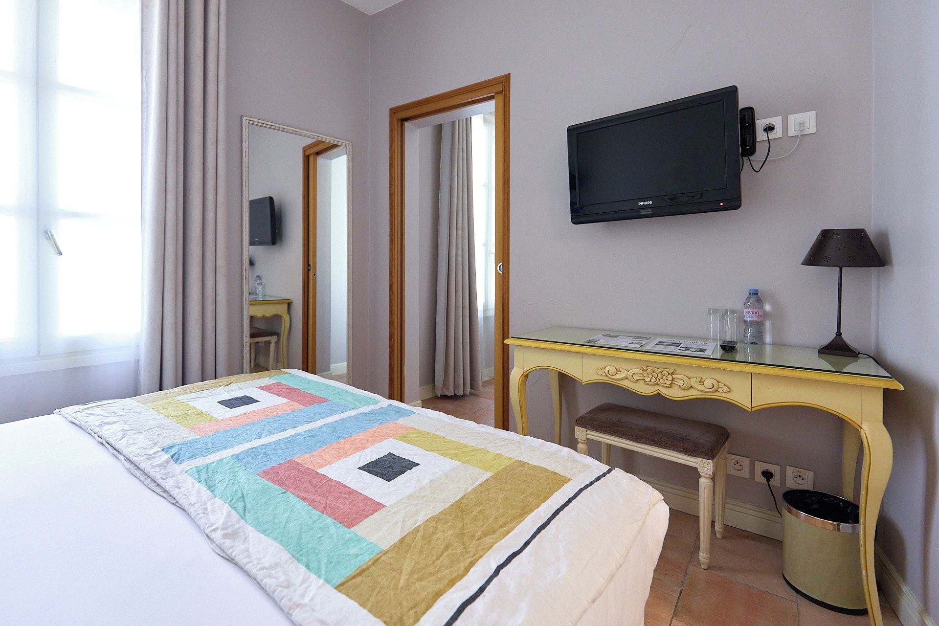 Une chambre d’hôtel avec un lit, un bureau, une télévision, une chaise et une lampe.
