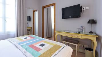 Une chambre d’hôtel avec un lit, un bureau, une télévision, une chaise et une lampe.