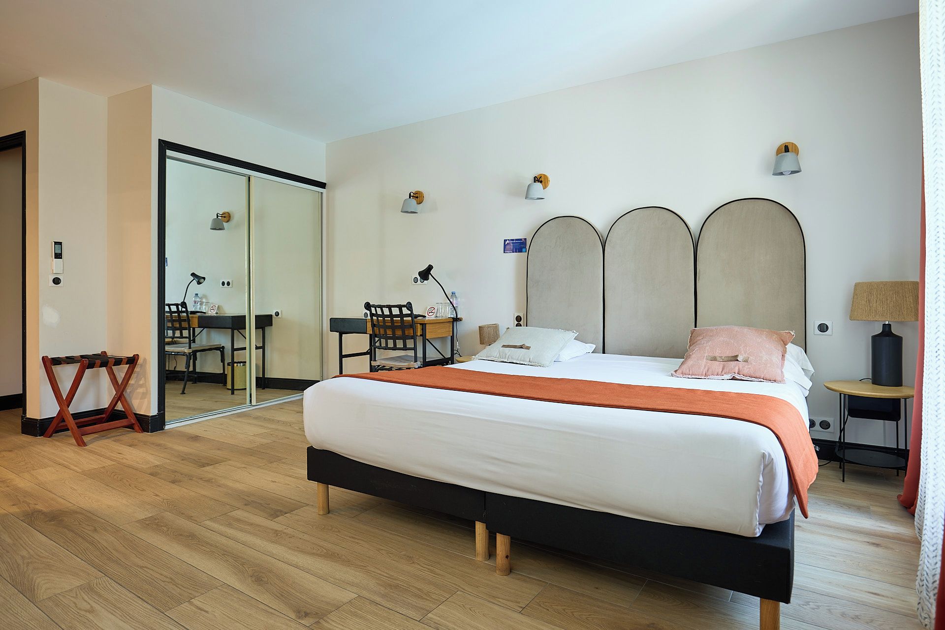 A hotel room with a bed, a desk, and a chair.