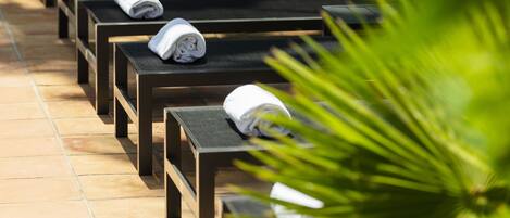 A row of wooden benches with towels on them, lined up on a tiled patio area.