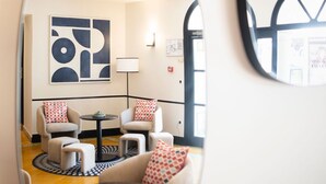 A modern interior with a sofa set, a small table, and a large abstract painting on the wall. - Hôtel l'Arena (Fréjus)
