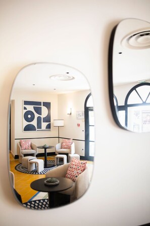 A modern interior with a sofa set, a small table, and a large abstract painting on the wall. - Hôtel l'Arena (Fréjus)