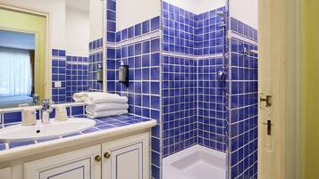 Un bagno con lavandino, specchio e box doccia rivestito in piastrelle blu.