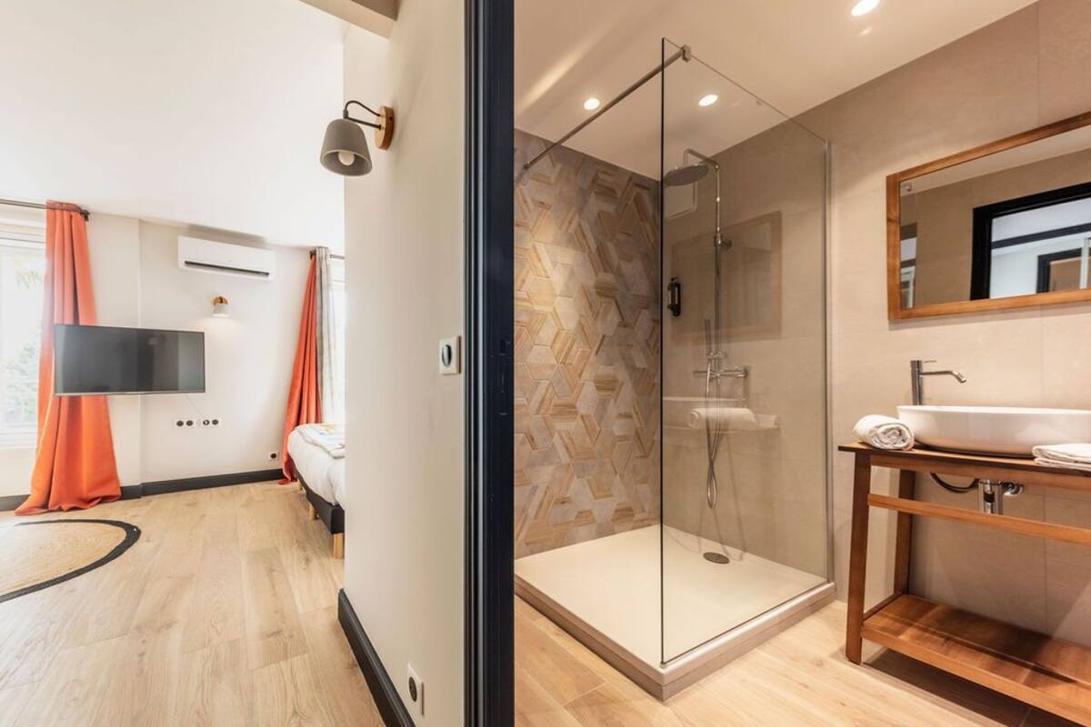 Un baño moderno con ducha de vidrio, tocador de madera y un espejo grande.
