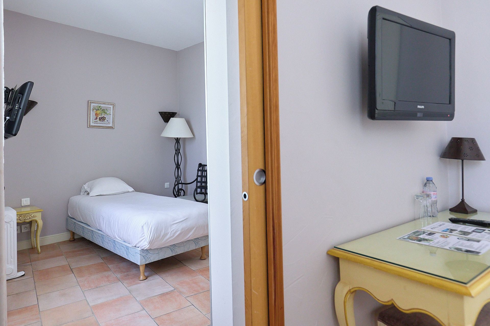 Una habitación de hotel con cama, escritorio, televisión y lámpara.