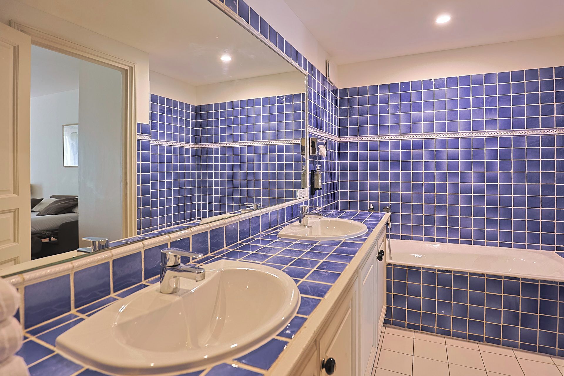A bathroom with two sinks, a bathtub, and a large mirror.