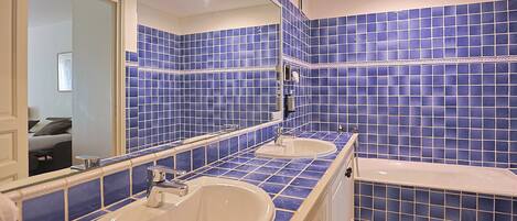 A bathroom with two sinks, a bathtub, and a large mirror.