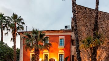 Un hotel con piscina, palmeras y un atardecer.