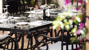 An outdoor dining area with tables set for two, surrounded by black wicker chairs. - Hôtel l'Arena (Fréjus)
