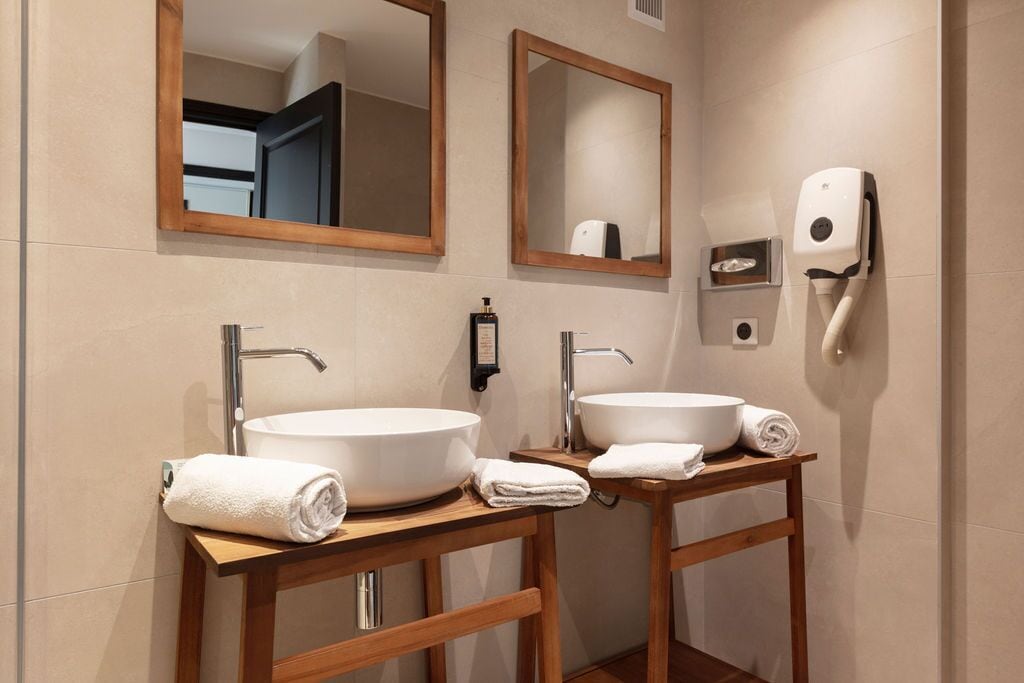 Une salle de bain avec deux lavabos, des meubles-lavabos en bois et un sèche-mains.