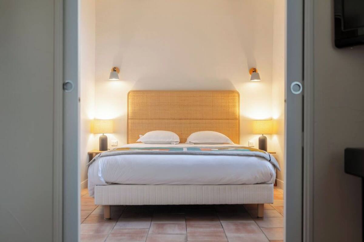 Un dormitorio con cama, dos lámparas de noche y cabecera.