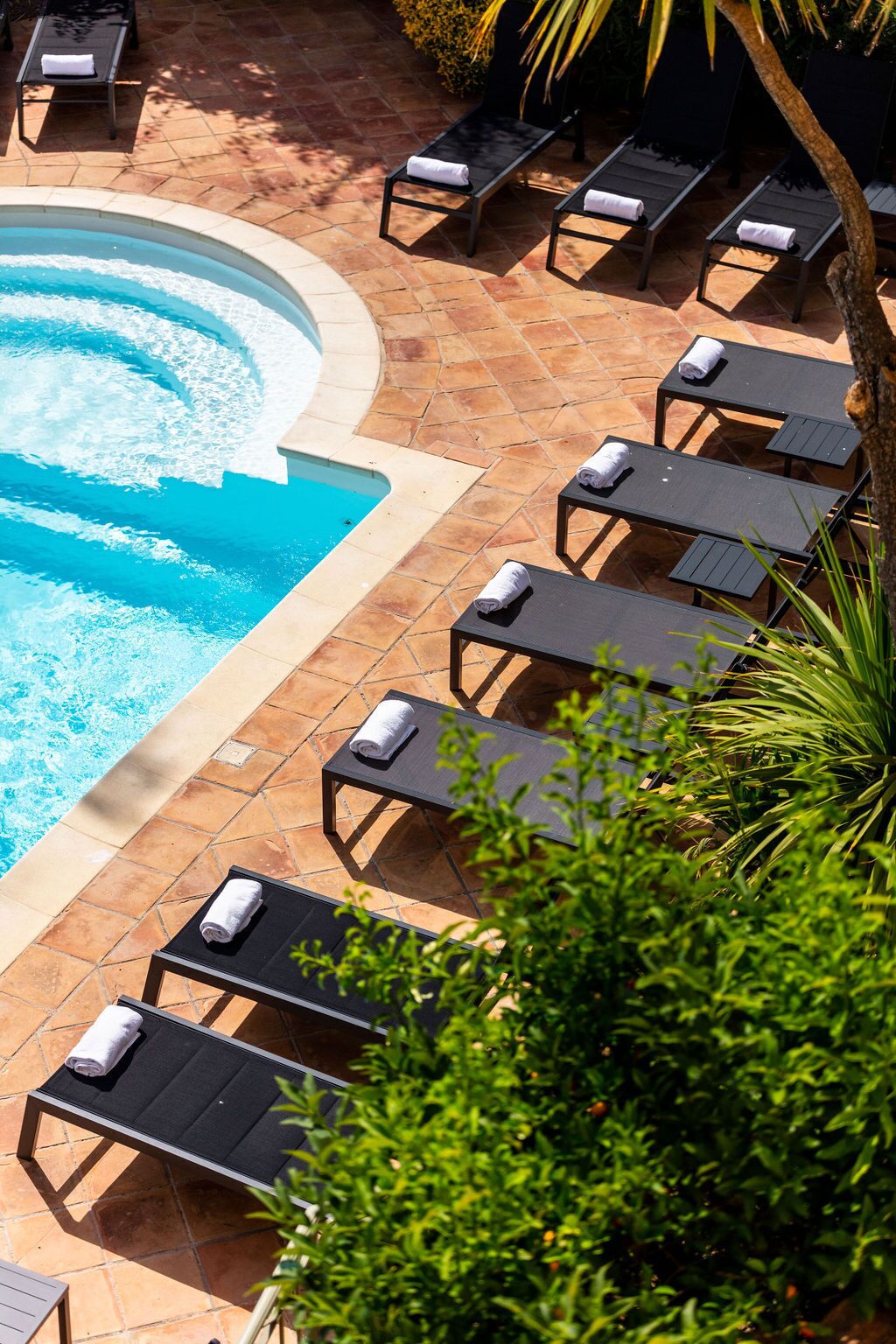 A pool area with lounge chairs and a tiled deck.
