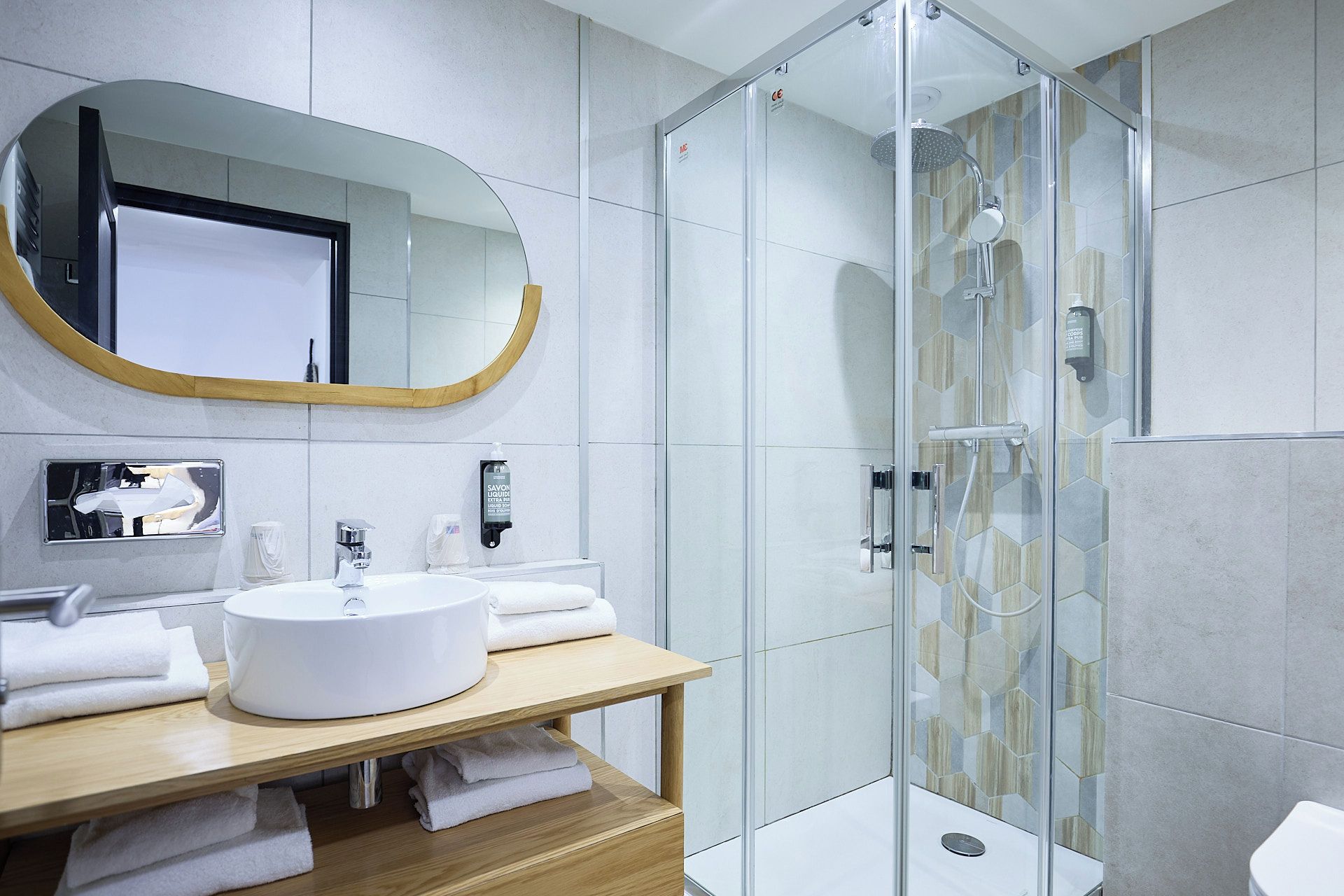 A modern bathroom with a glass-enclosed shower, a round sink, and a wooden vanity.