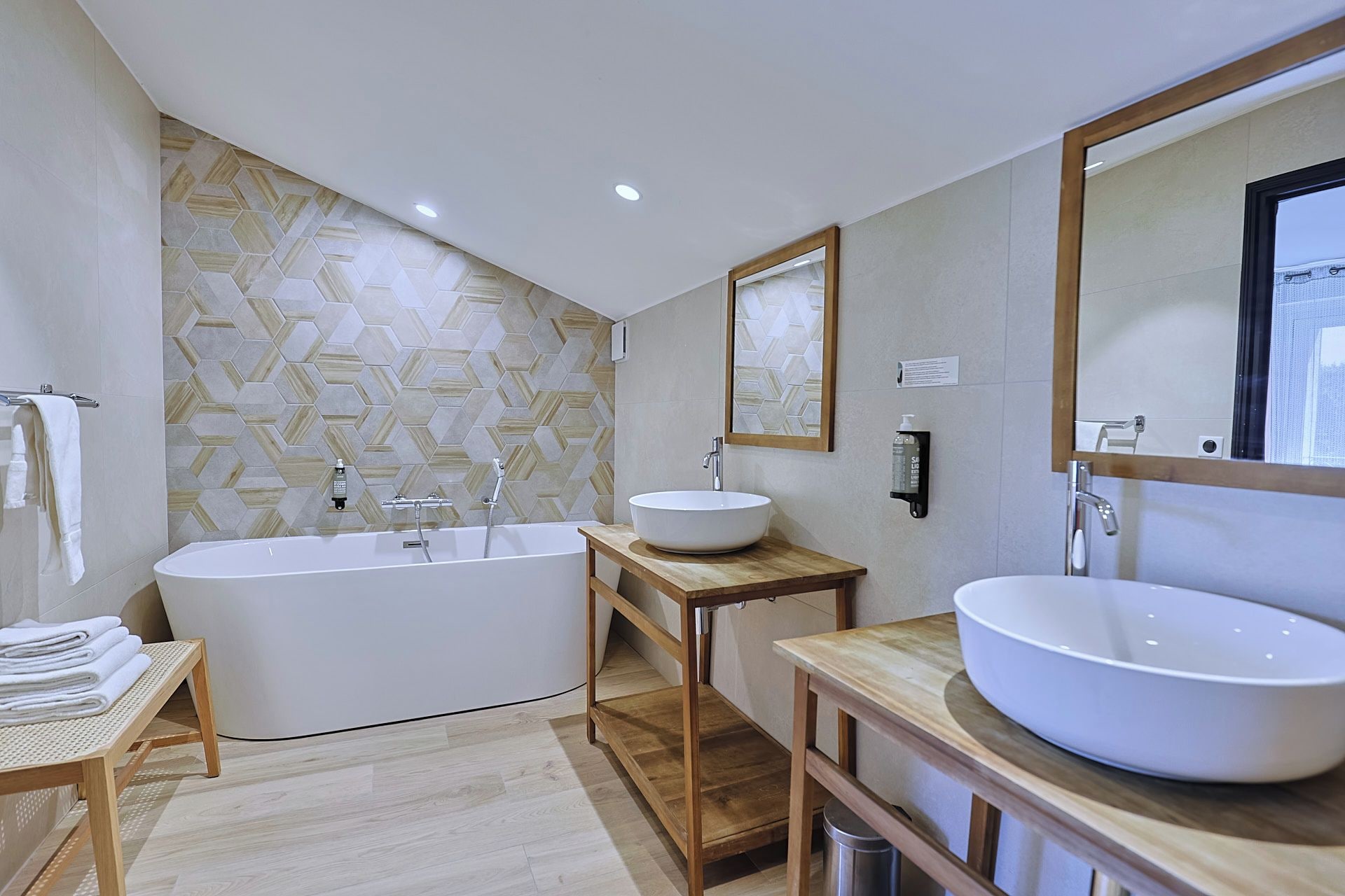 A modern bathroom with a freestanding bathtub, two sinks, and a large mirror.