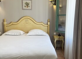 Una cama con cabecera dorada, ropa de cama blanca y una mesita de noche pequeña con una lámpara.